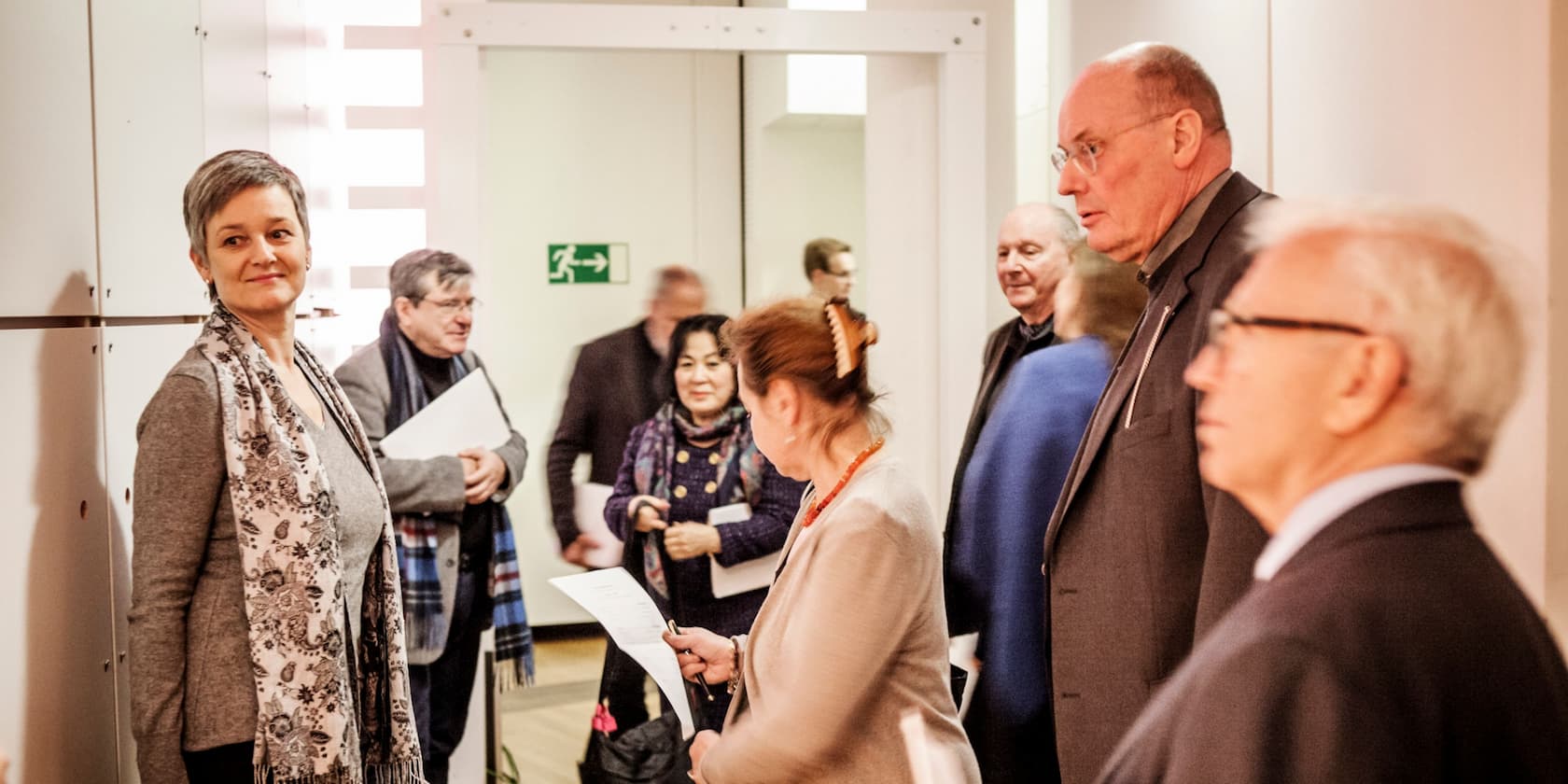 Group of people in a hallway, some holding documents.