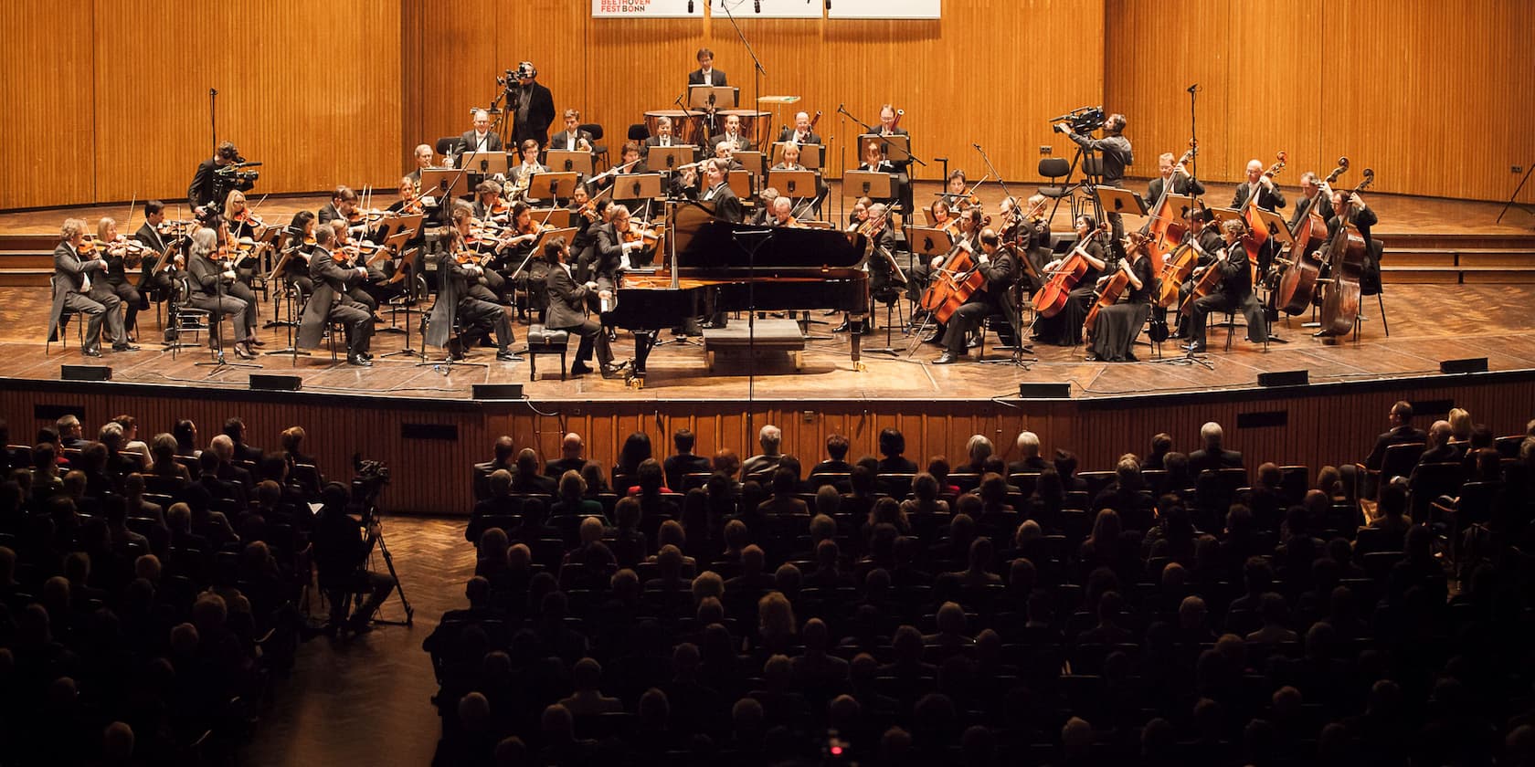 An orchestra performs on a stage in front of an audience.