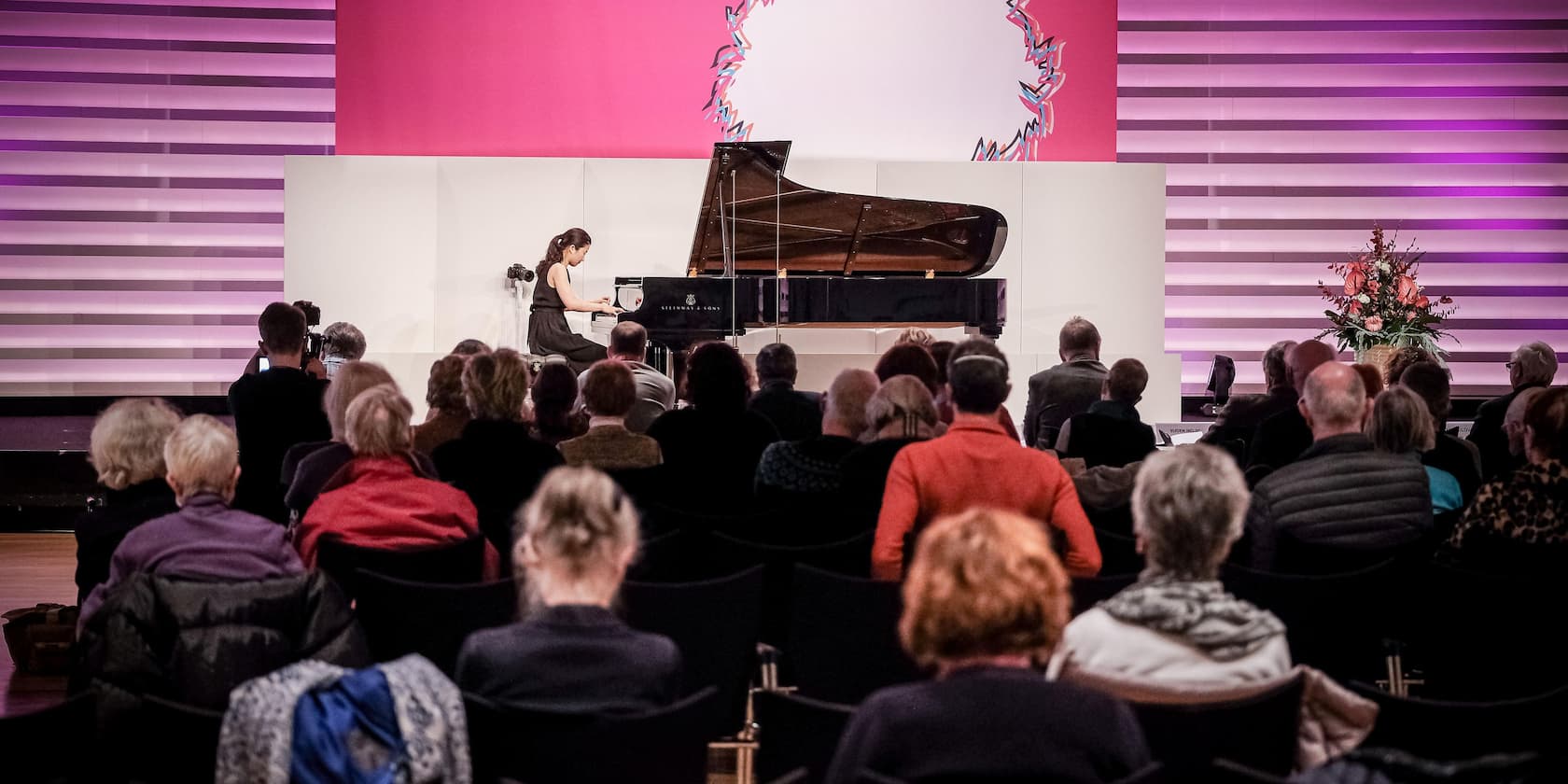 A woman is playing the piano in front of an audience.