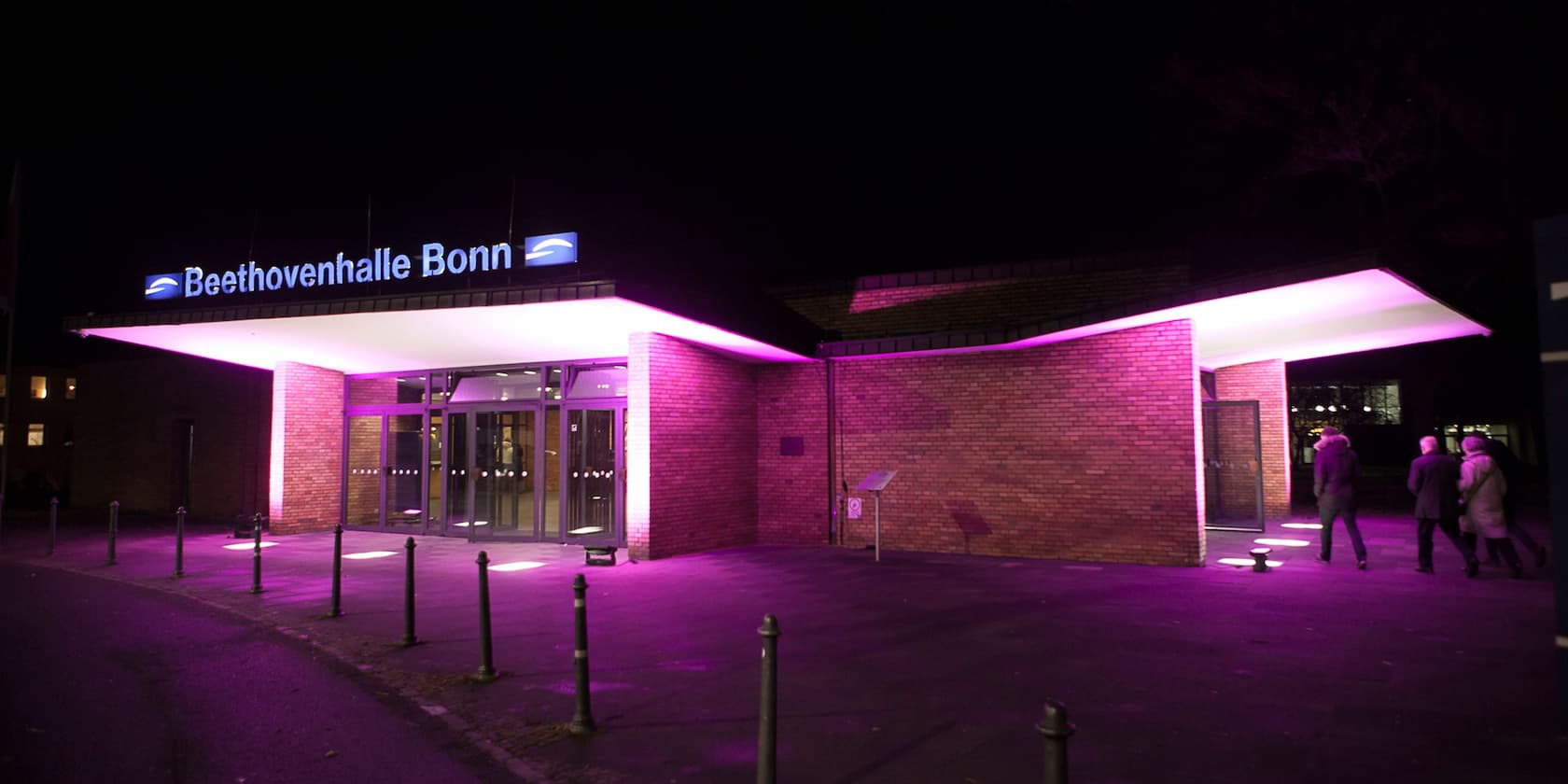 Entrance of Beethovenhalle Bonn at night with purple lighting.