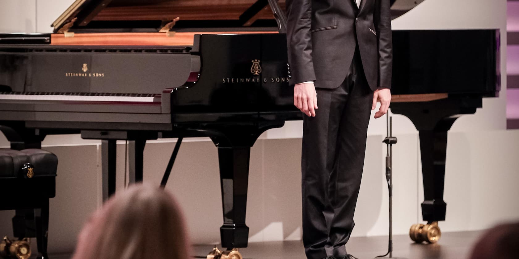 A man stands next to a Steinway & Sons grand piano.