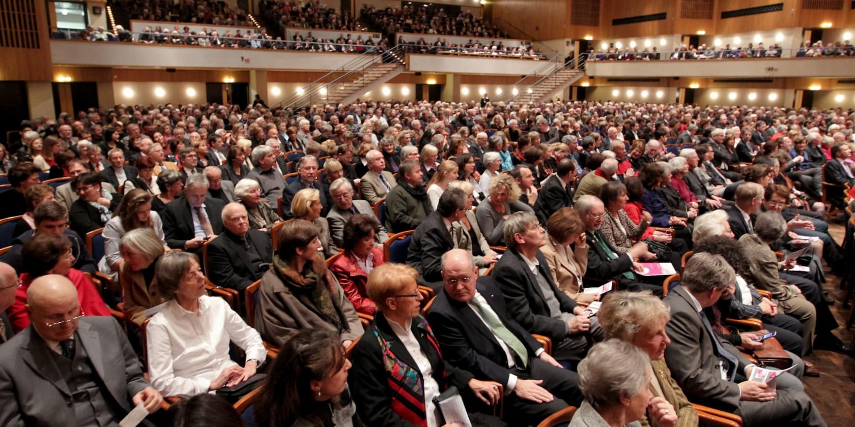 A large group of people seated in an auditorium attending an event.