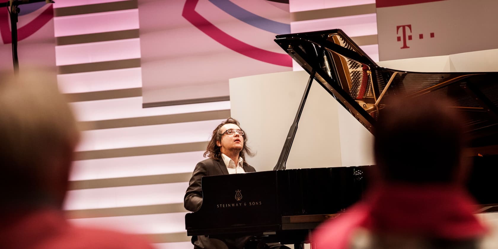 A pianist playing a Steinway & Sons piano during an event with the T-Mobile logo in the background.