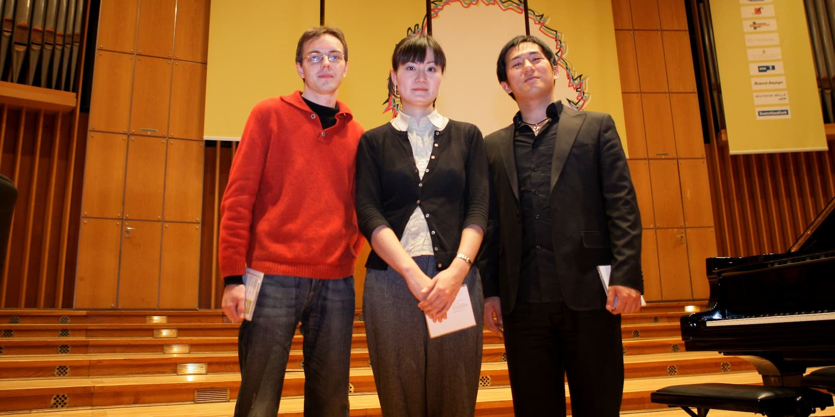 Three people standing side by side on a stage.