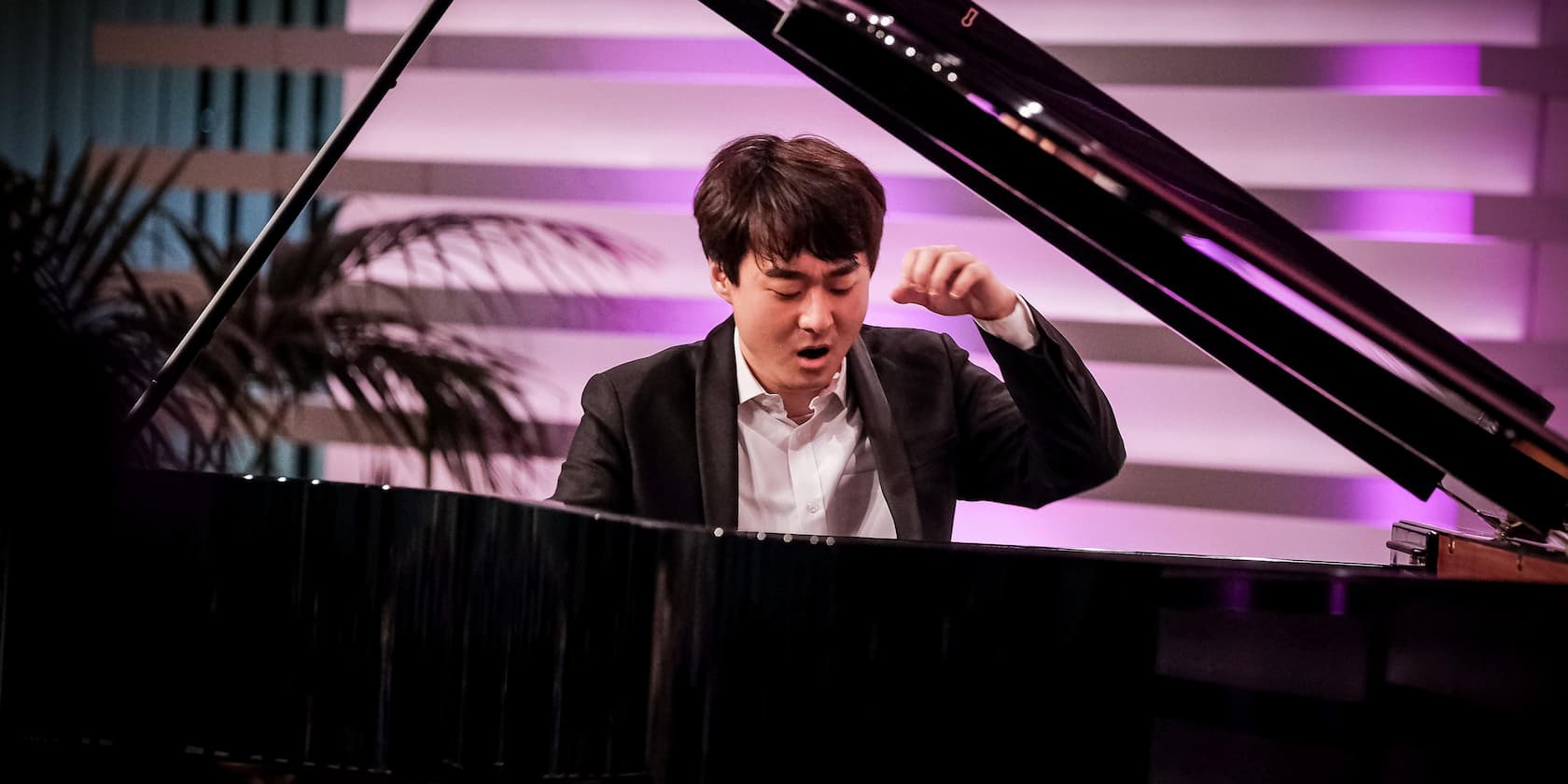 A man in formal attire is playing the piano.