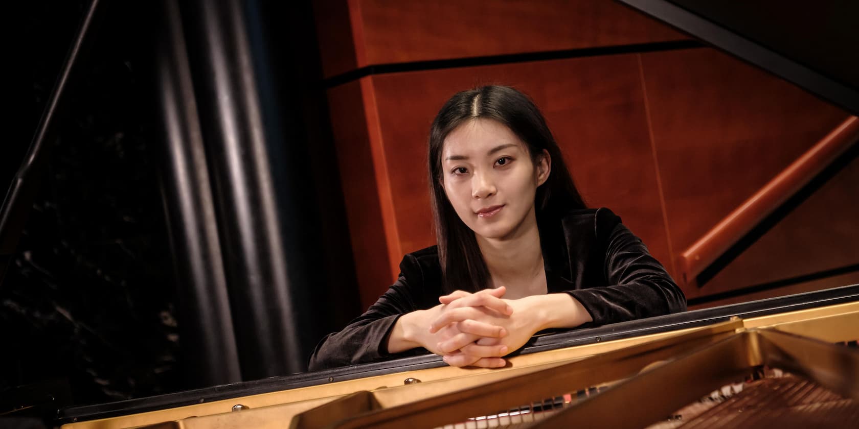 Woman leaning over a piano and smiling.