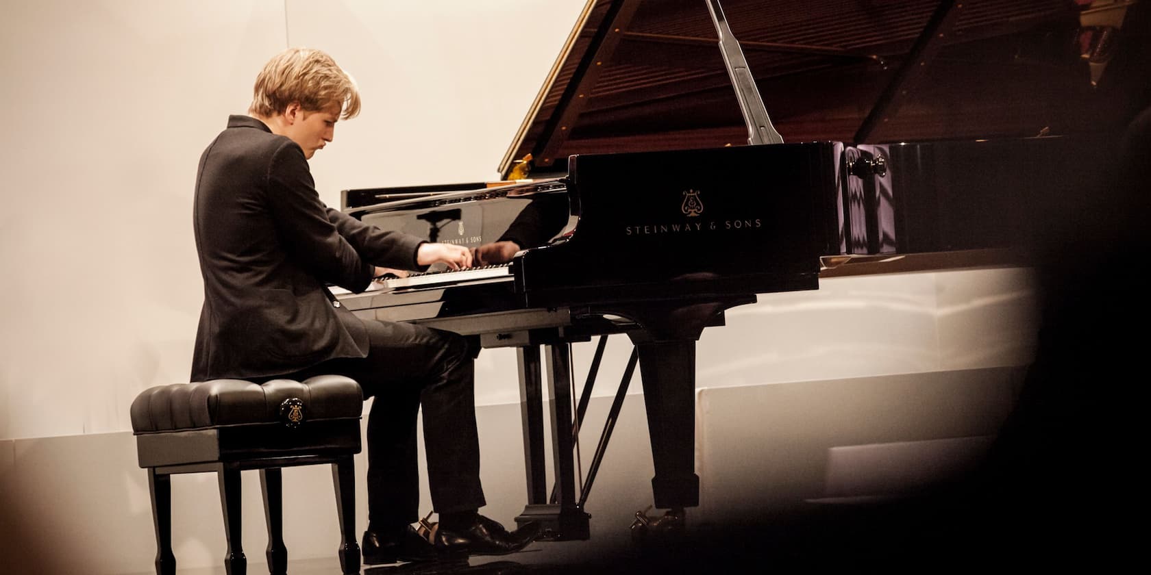 A pianist playing on a black Steinway & Sons grand piano.