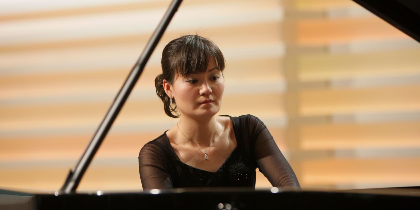 A woman playing the piano with a blurred background.