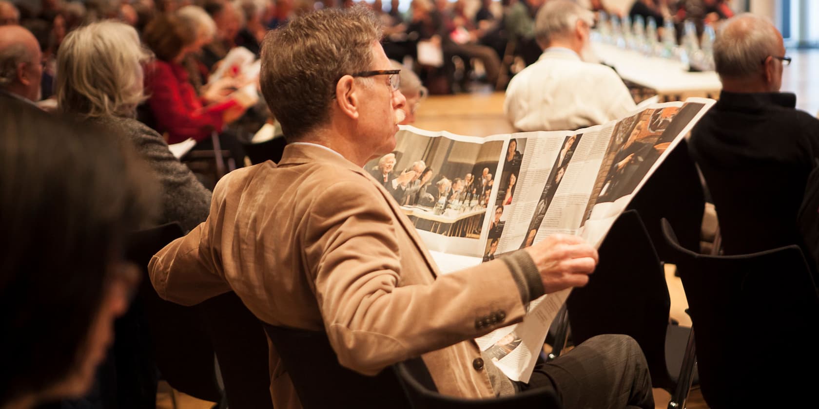 A man reads a newspaper in a crowd