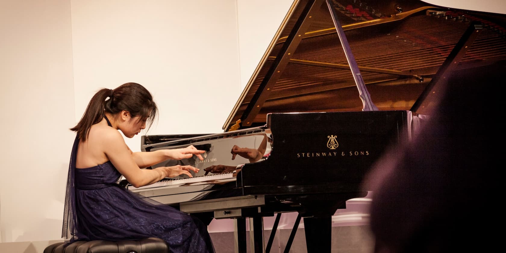 Woman playing a Steinway & Sons grand piano in a concert.