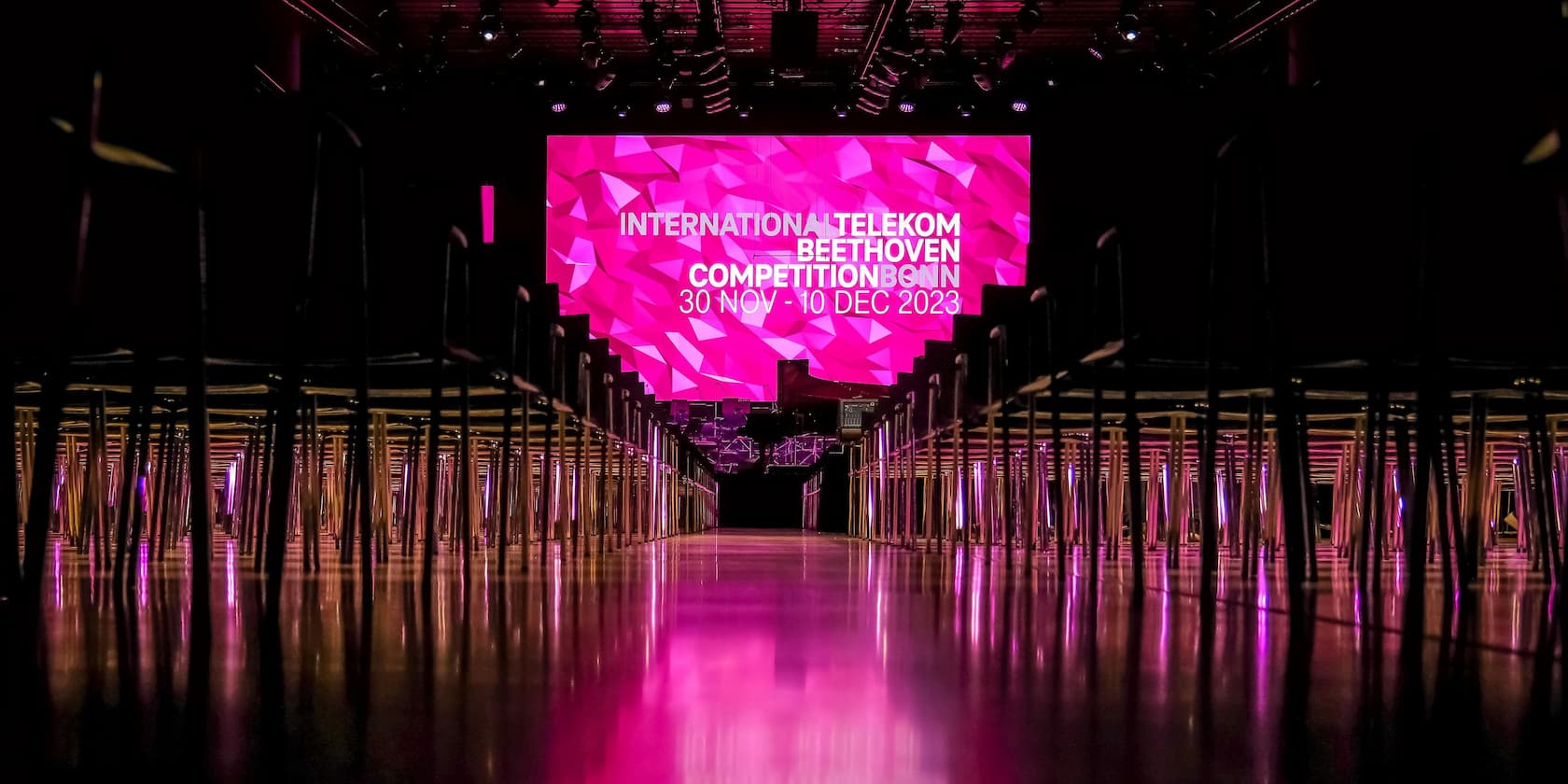 Leerer Konzertsaal mit einer beleuchteten Bühne und einem Plakat der Internationalen Telekom Beethoven Competition Bonn, 30. Nov-10. Dez 2023.