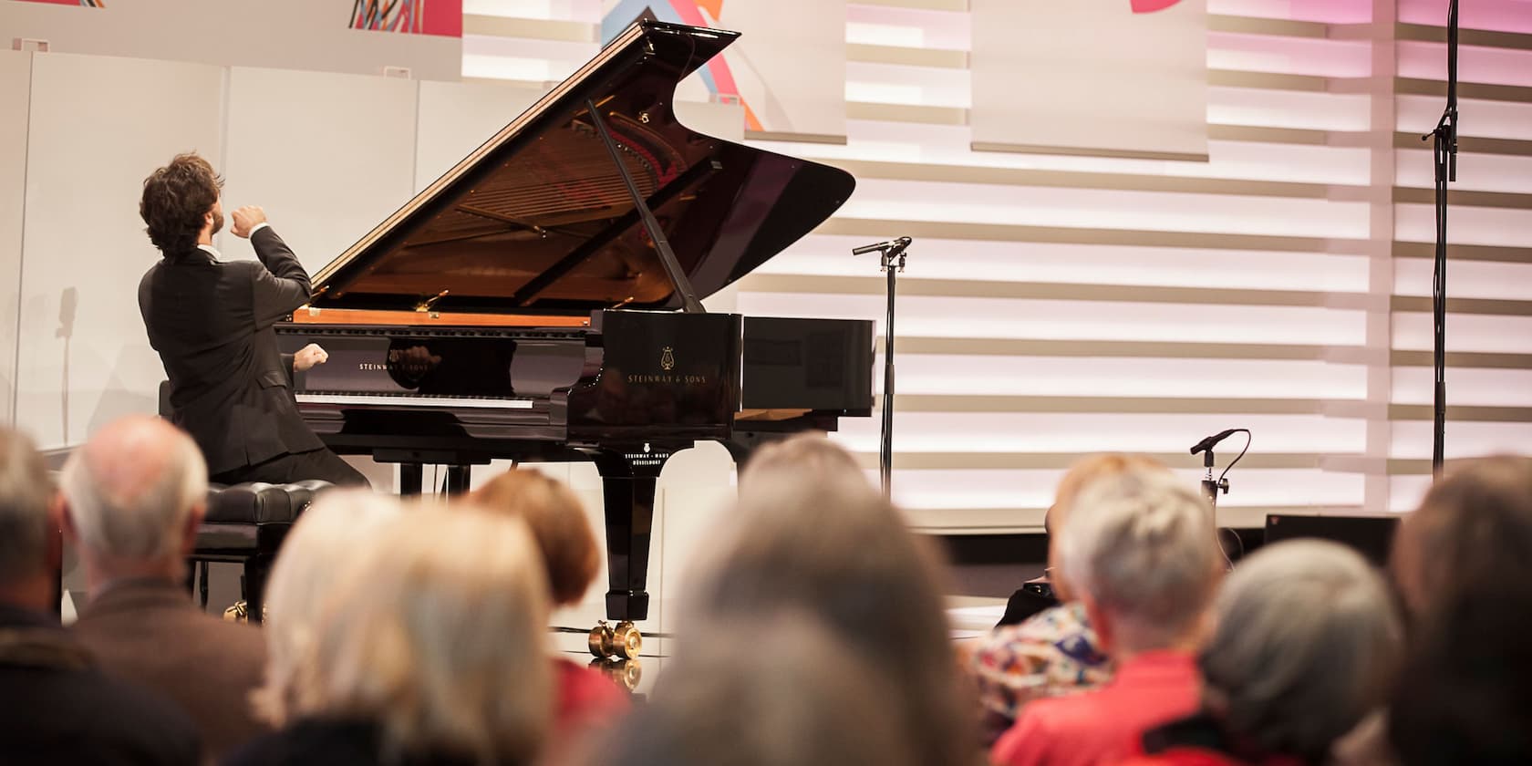 A man playing piano on a stage in front of an audience.