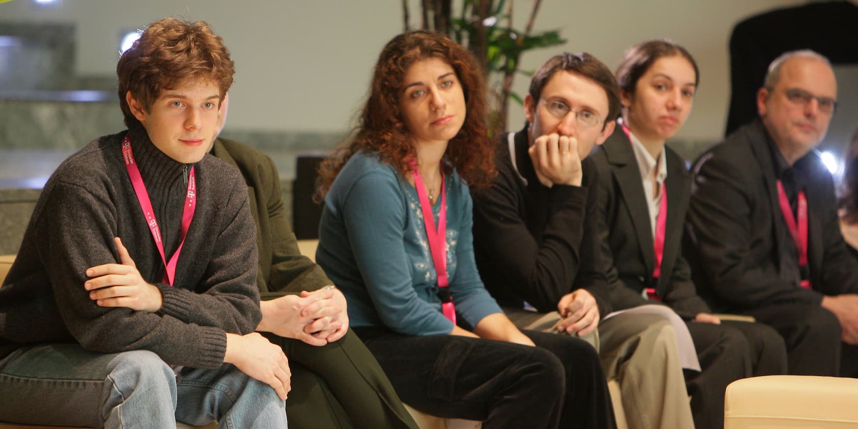 A group of five people sitting next to each other, wearing name badges.