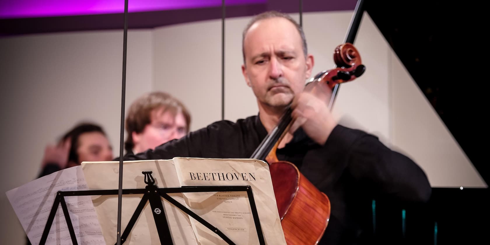 A musician performs a cello concert with a Beethoven music sheet.