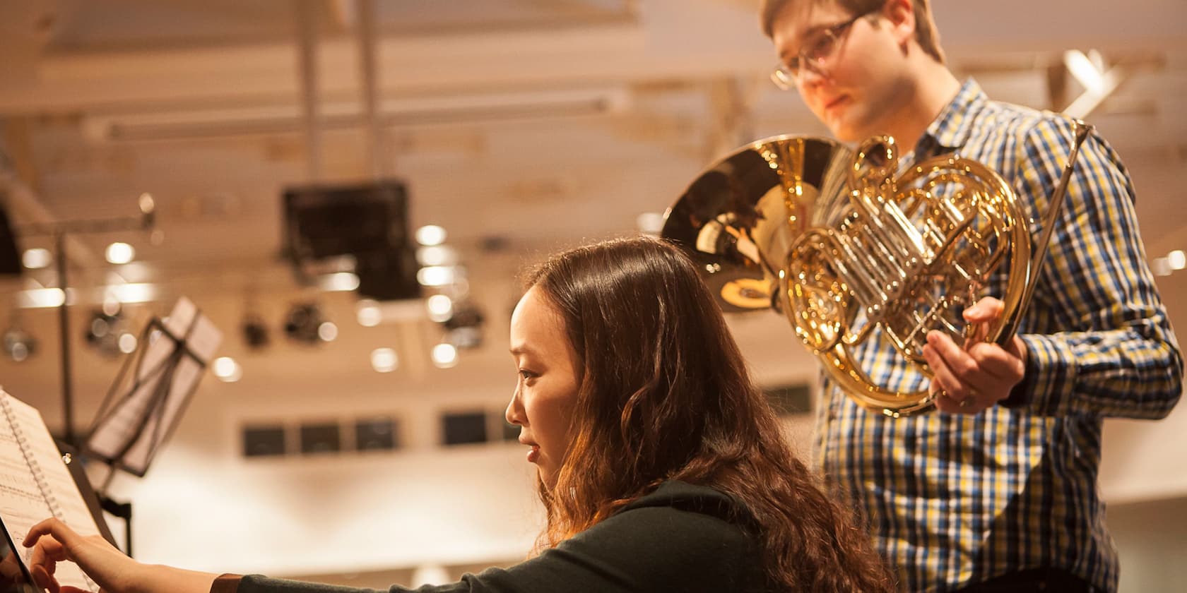 Eine Frau zeigt einem Hornspieler Musiknoten.