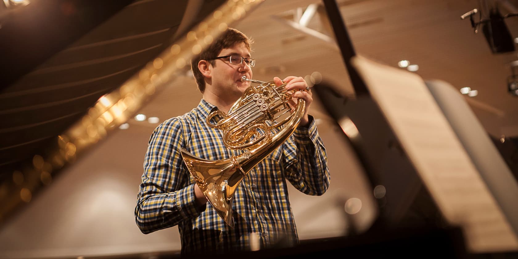 Man playing a French horn in a concert hall