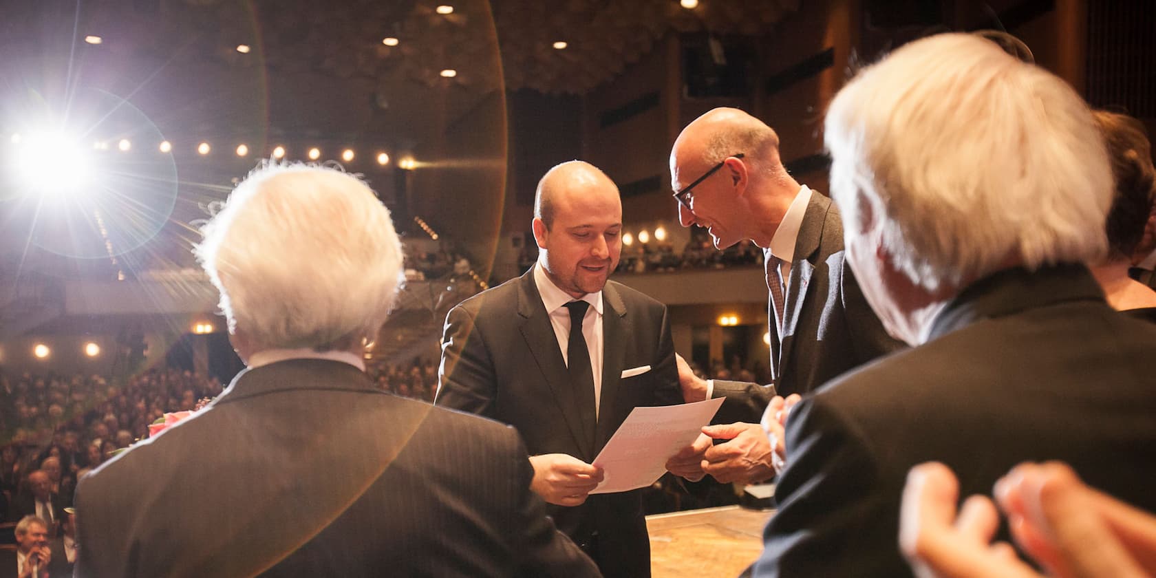 Man in a suit receiving a certificate on stage in front of an audience