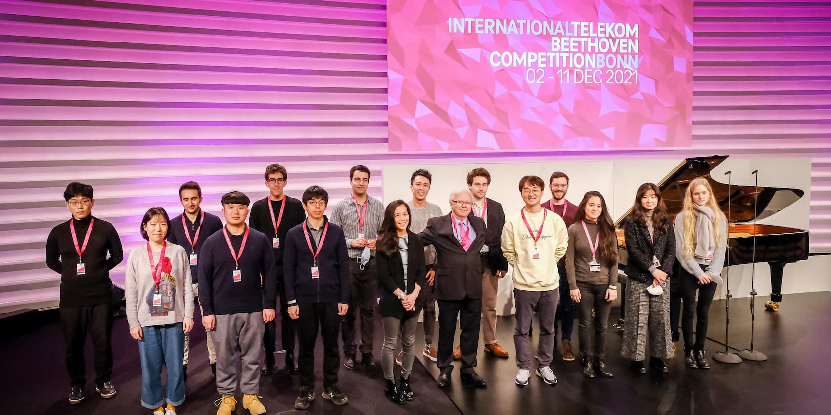 Participants posing on stage at the International Telekom Beethoven Competition Bonn 2021 in front of a grand piano.