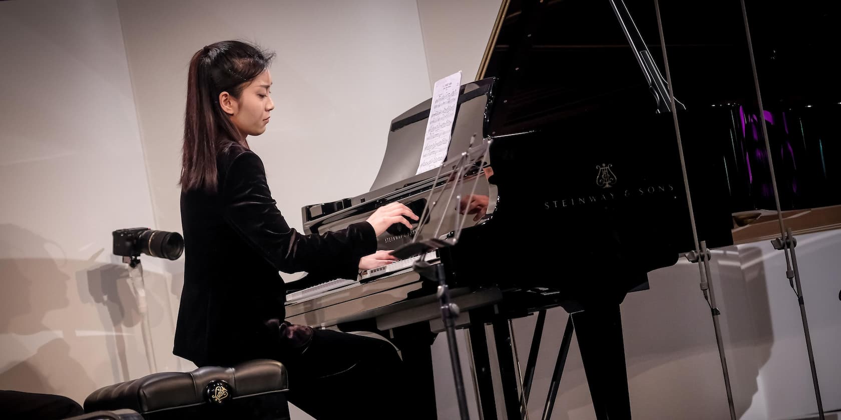 A woman playing piano in a concert hall.