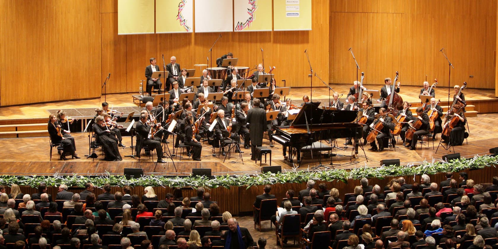 An orchestra performing on stage in front of an audience.