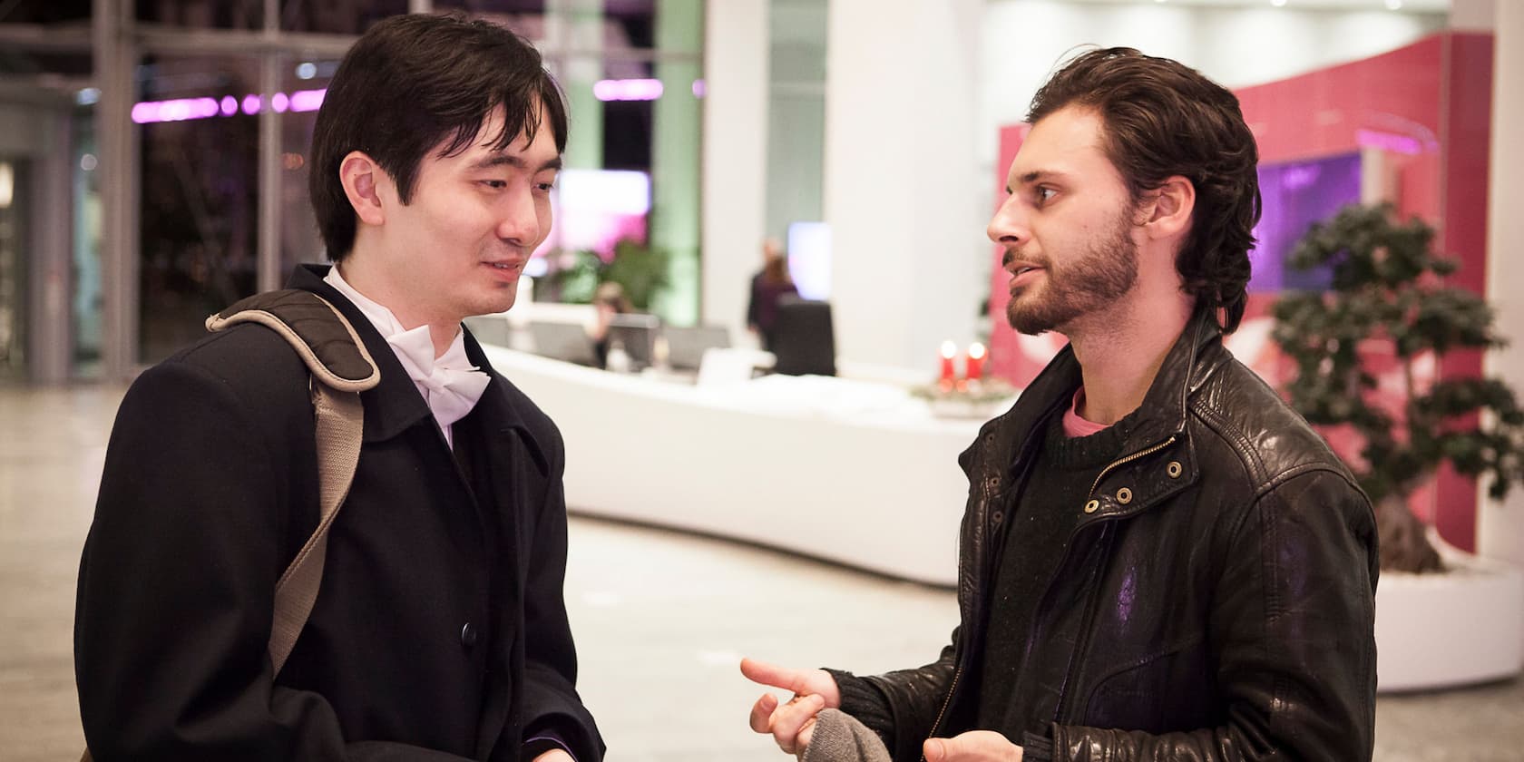 Two men standing in a modern reception area having a conversation.