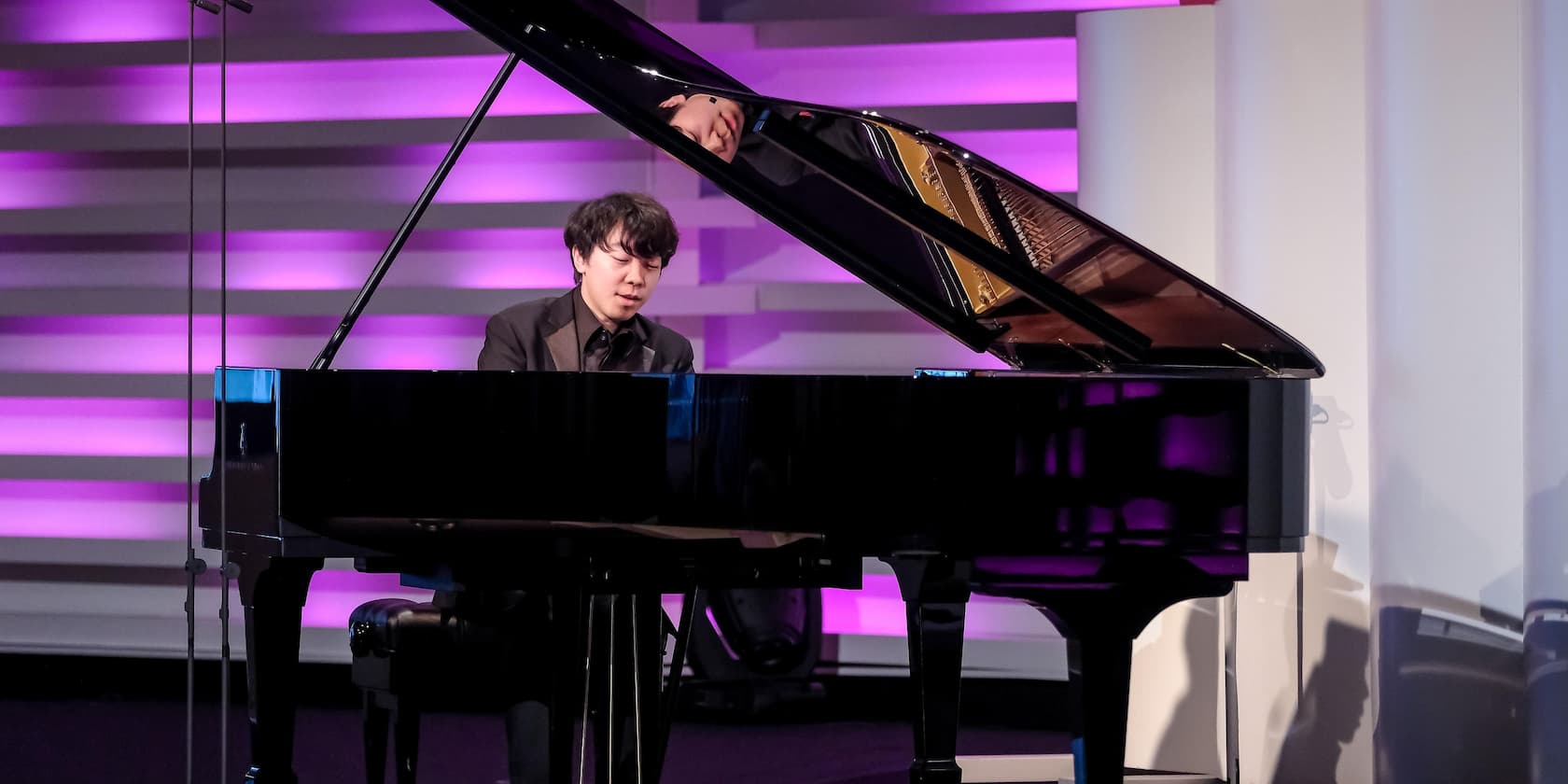 A man playing the piano in a lit room