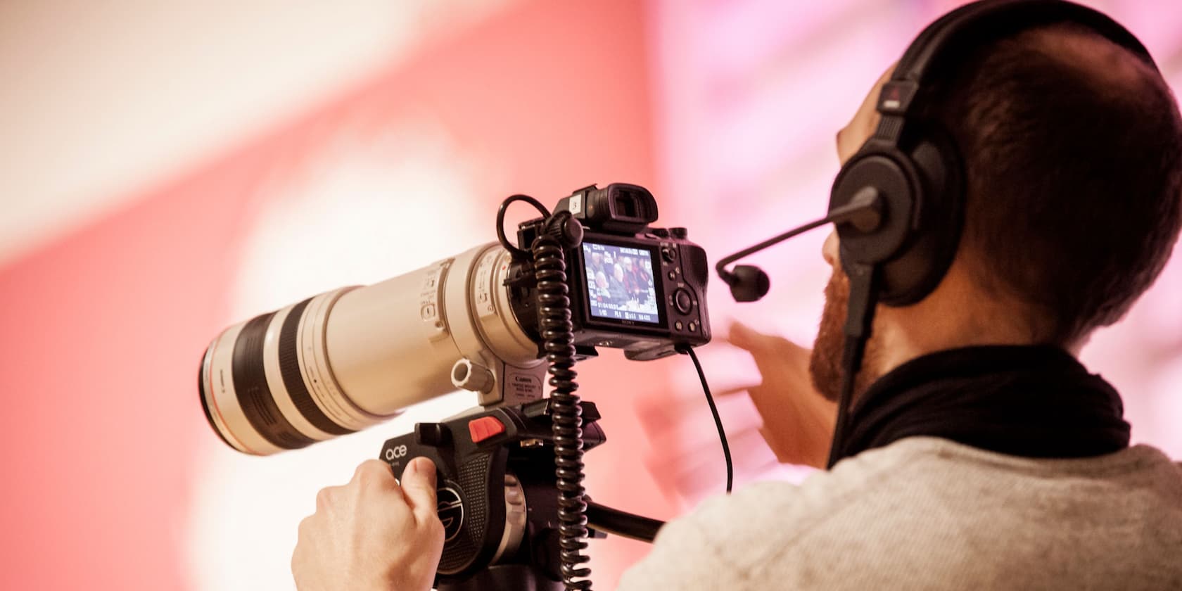 A cameraman wearing headphones is filming with a professional camera.