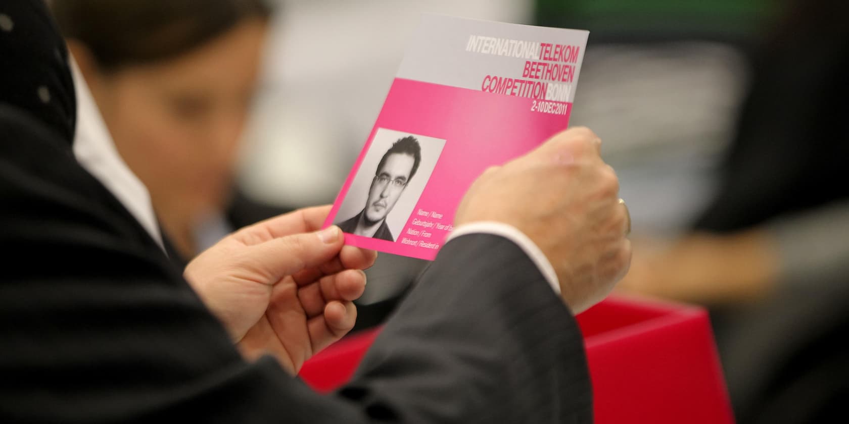 A person holding a program booklet for the International Telekom Beethoven Competition Bonn, showing a portrait of a man.