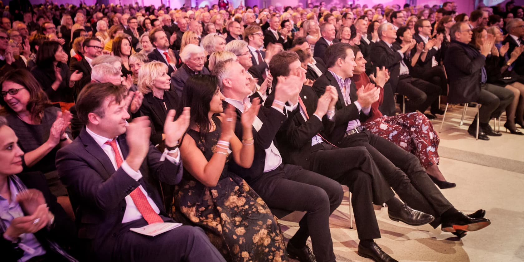 A group of people sitting and clapping at an event.