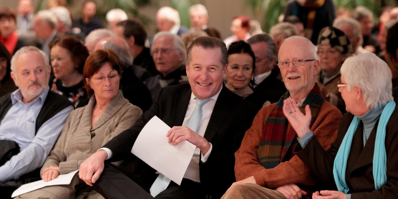 A group of people sitting close together and smiling at an event.