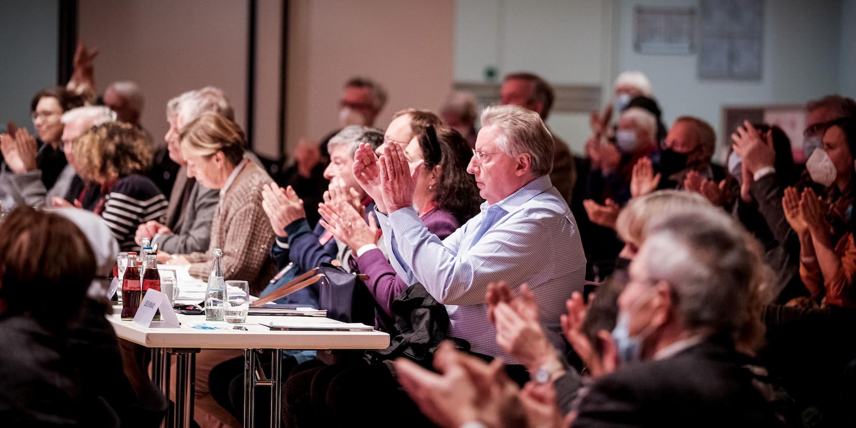 Group of people clapping during an event in a conference room.