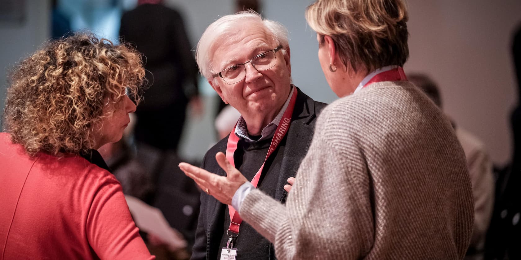 Drei Personen unterhalten sich in einer Konferenz.