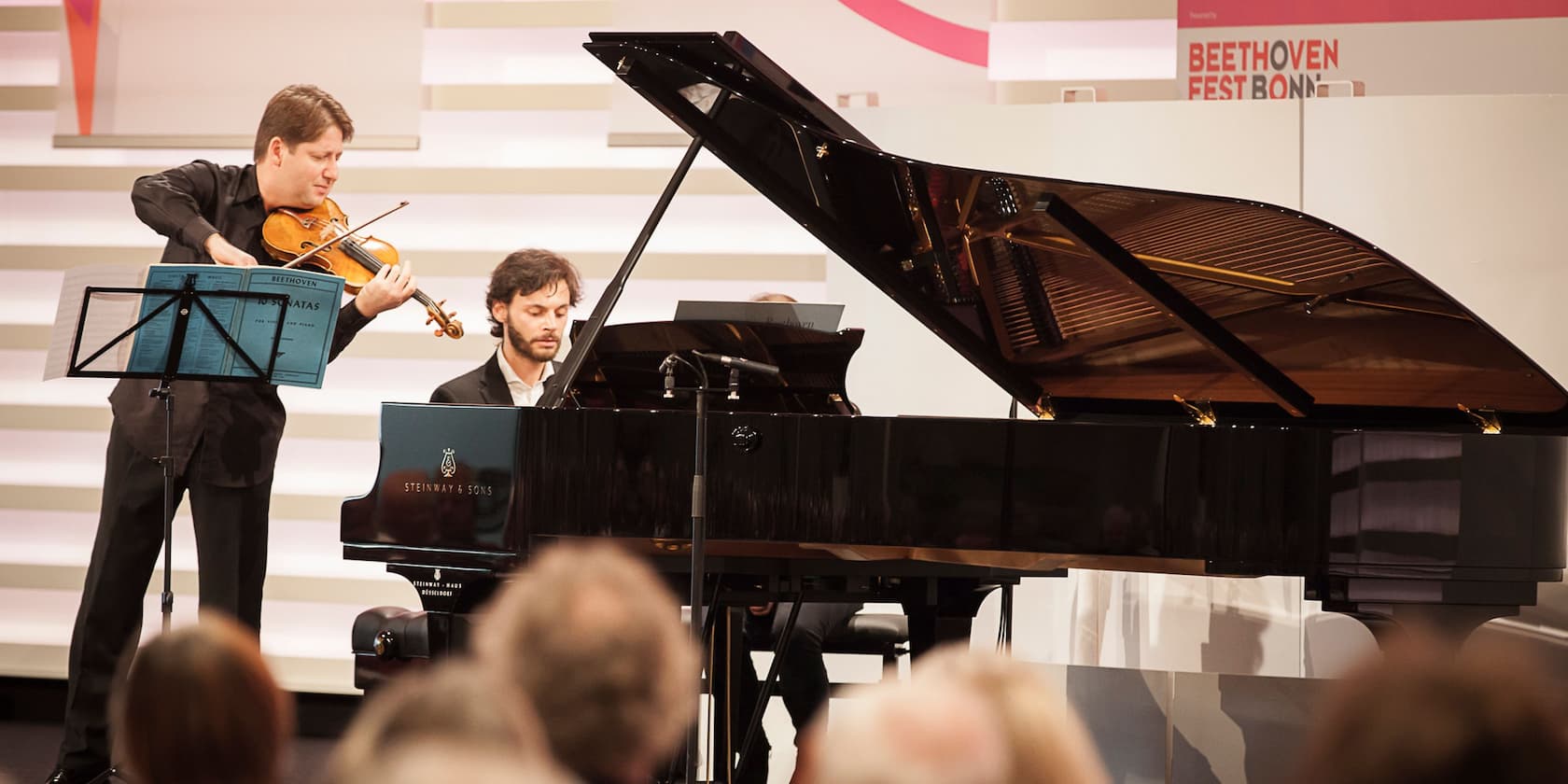 Two musicians performing during the Beethoven Festival in Bonn: a violinist and a pianist at a grand piano.