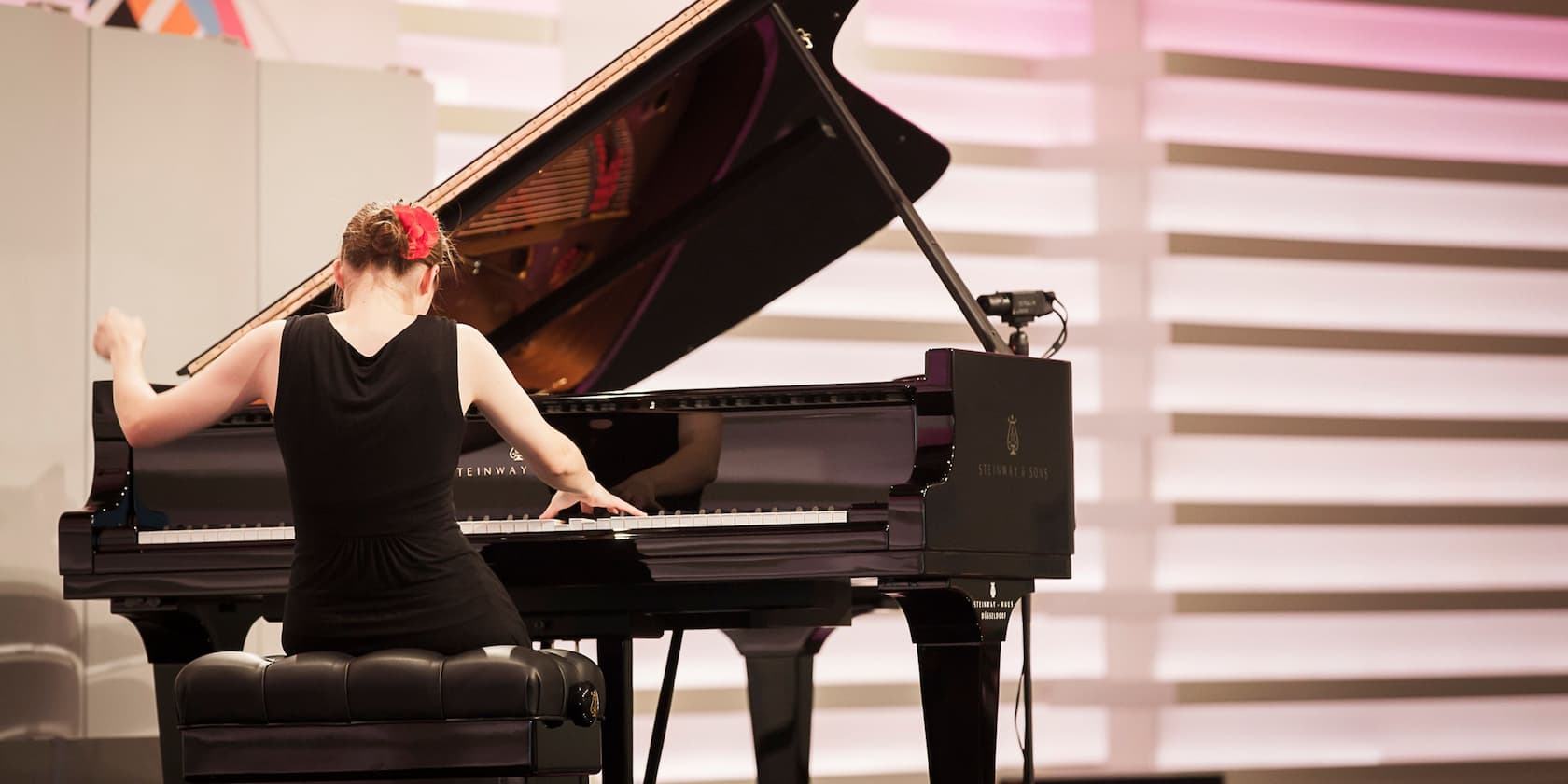 A woman playing piano in a concert hall.