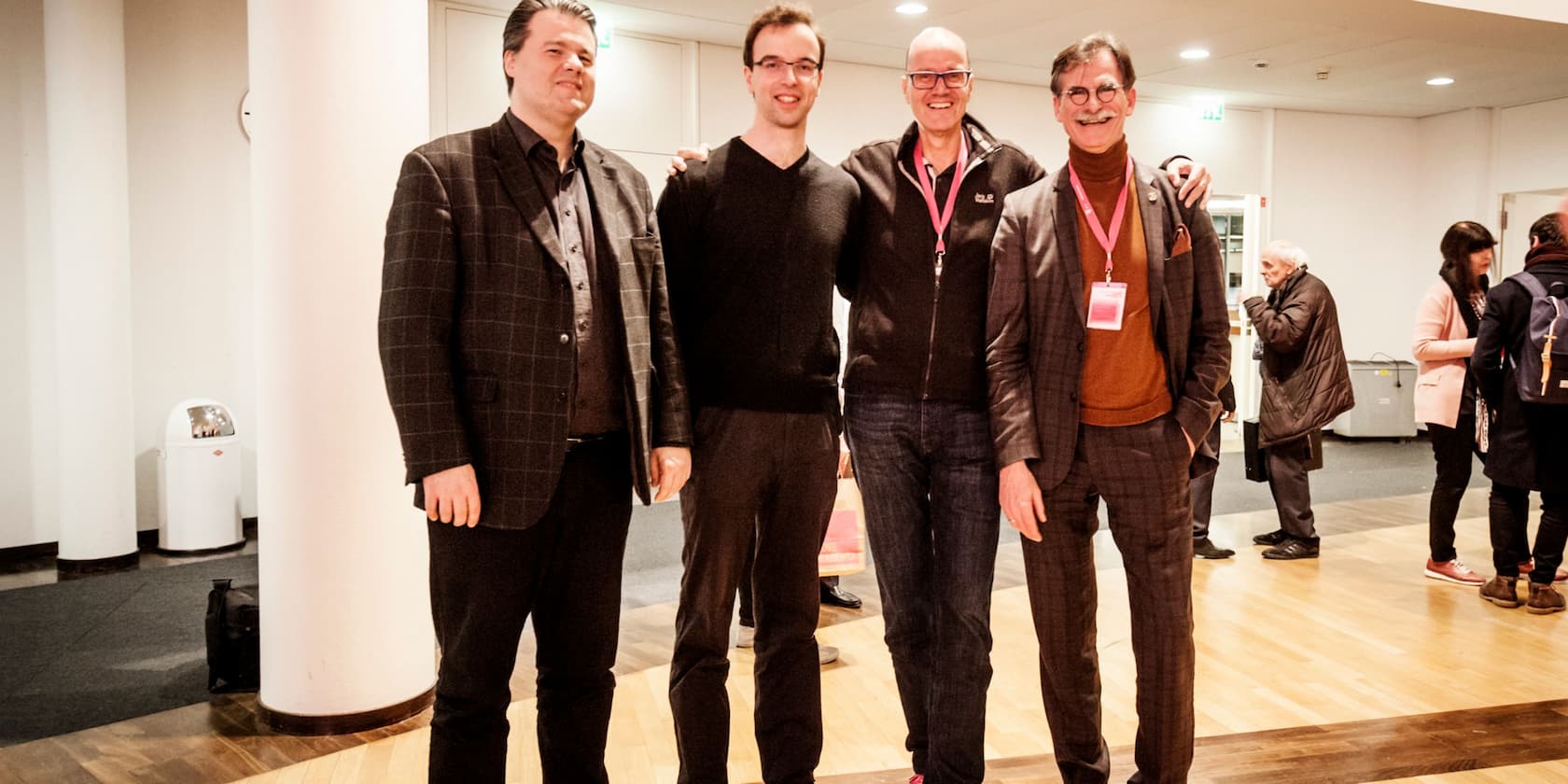 Four men posing for a photo in a conference room.