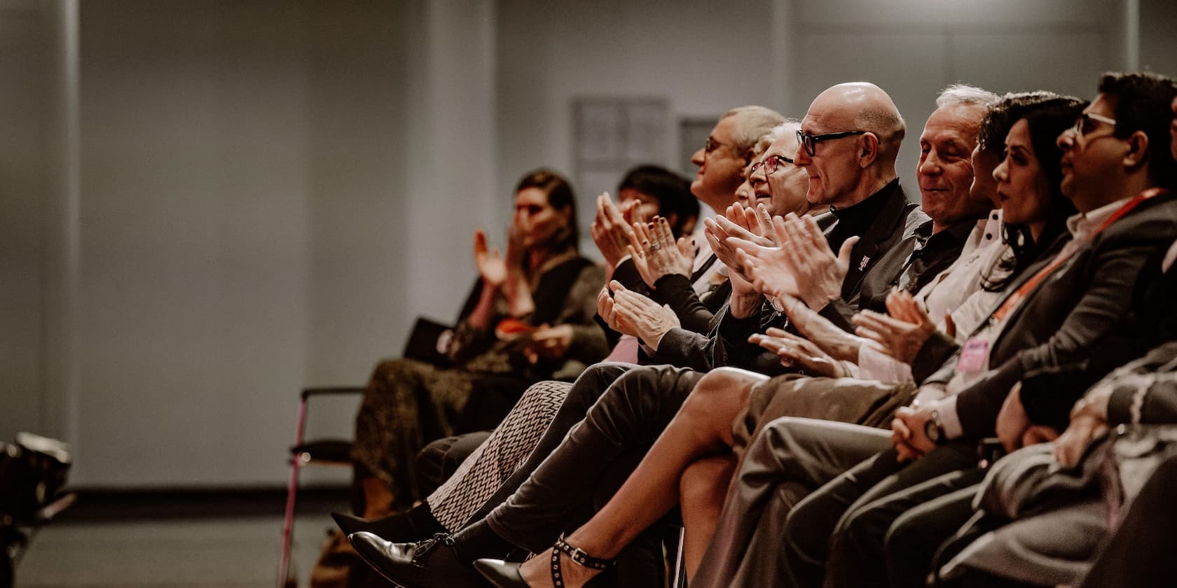 Several people sitting and clapping in a conference room.