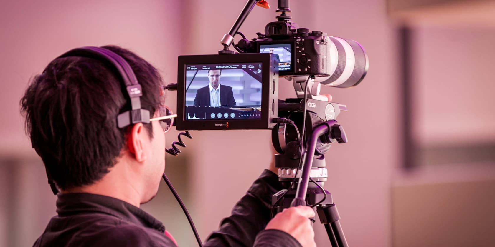 A person films another person with a camera and monitor.