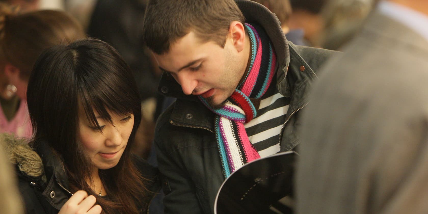 Two people stand close together and look down.