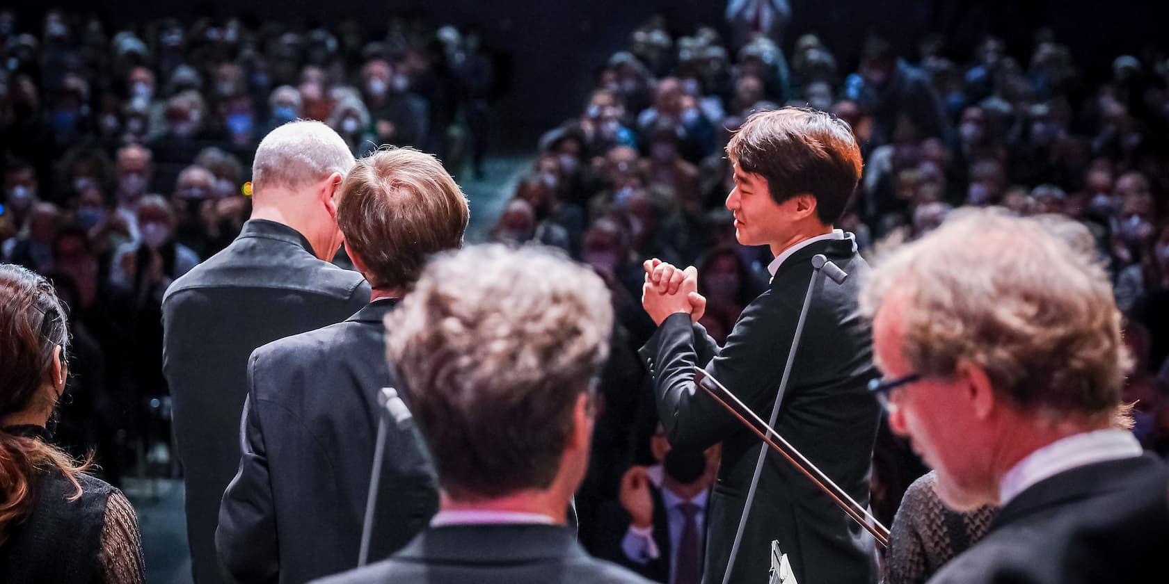 People on a stage in front of an audience, one person clapping