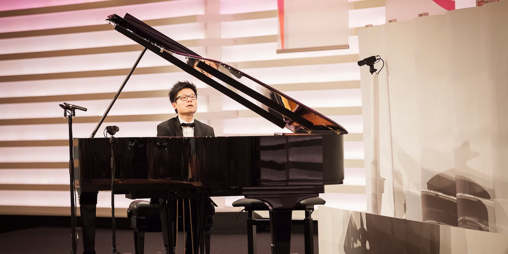 A pianist playing a grand piano on a stage.