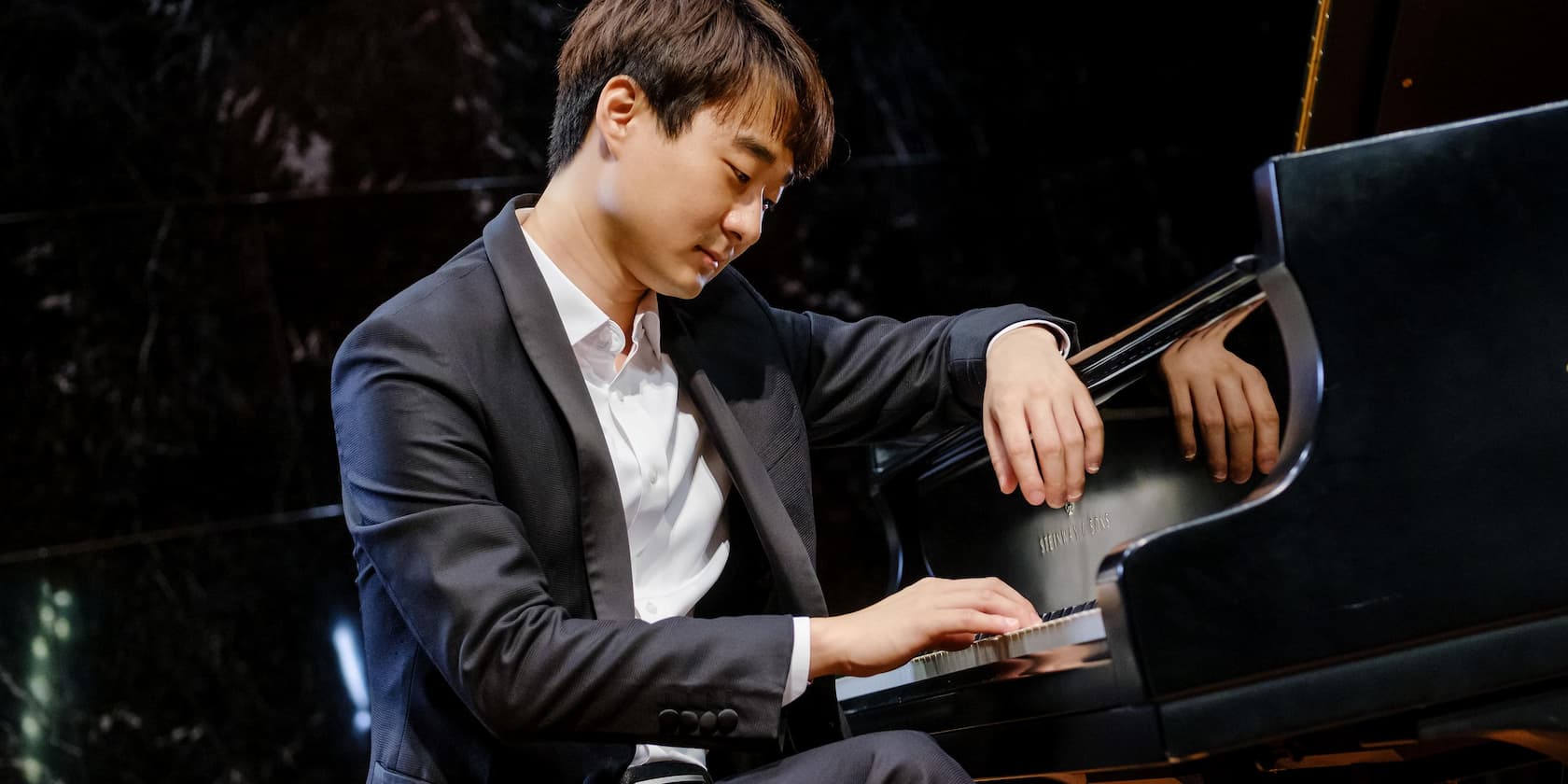 A man in a suit playing the piano.