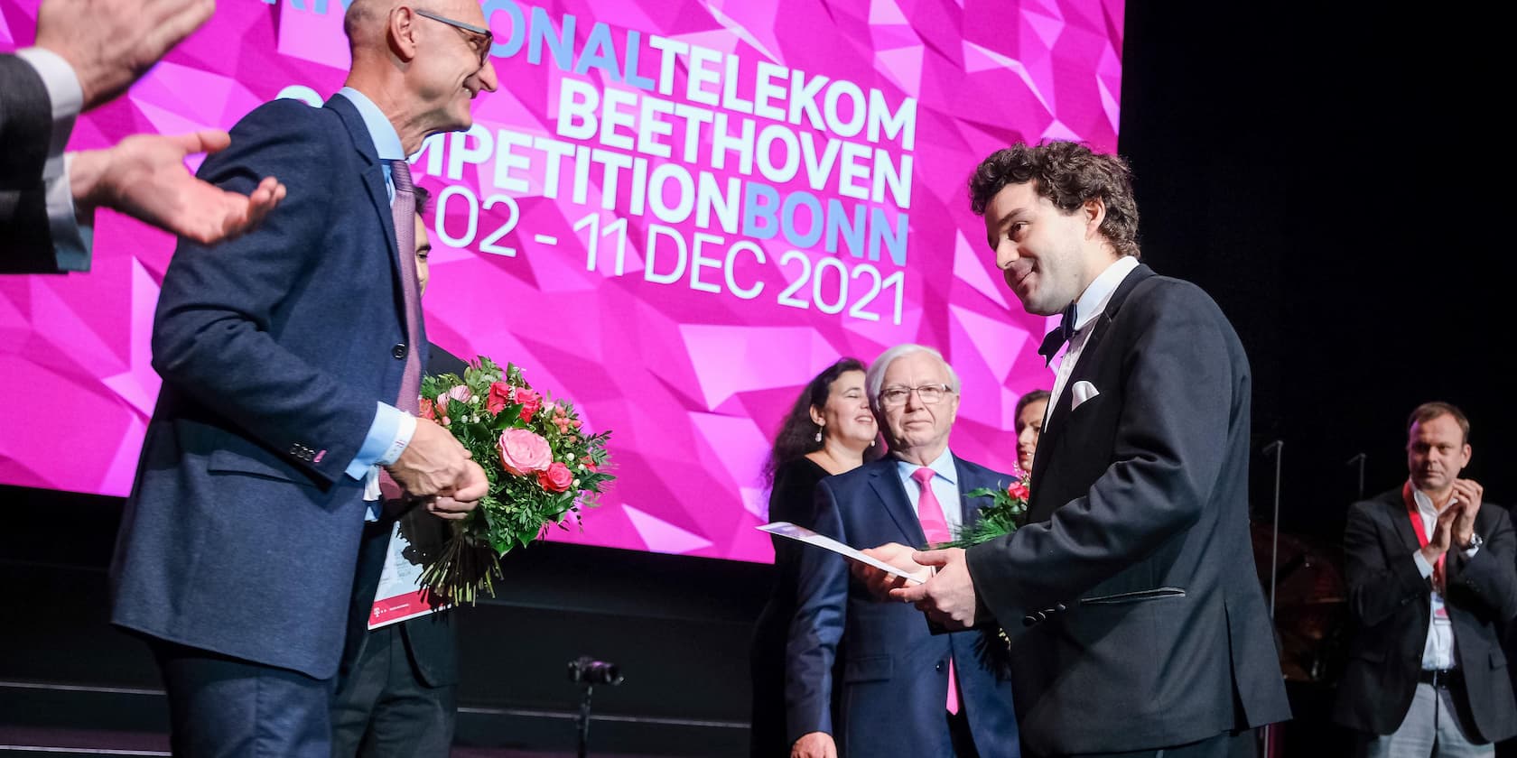 Teilnehmer erhält Auszeichnung bei der International Telekom Beethoven Competition Bonn 2021 vor einer großen rosa Bühne.