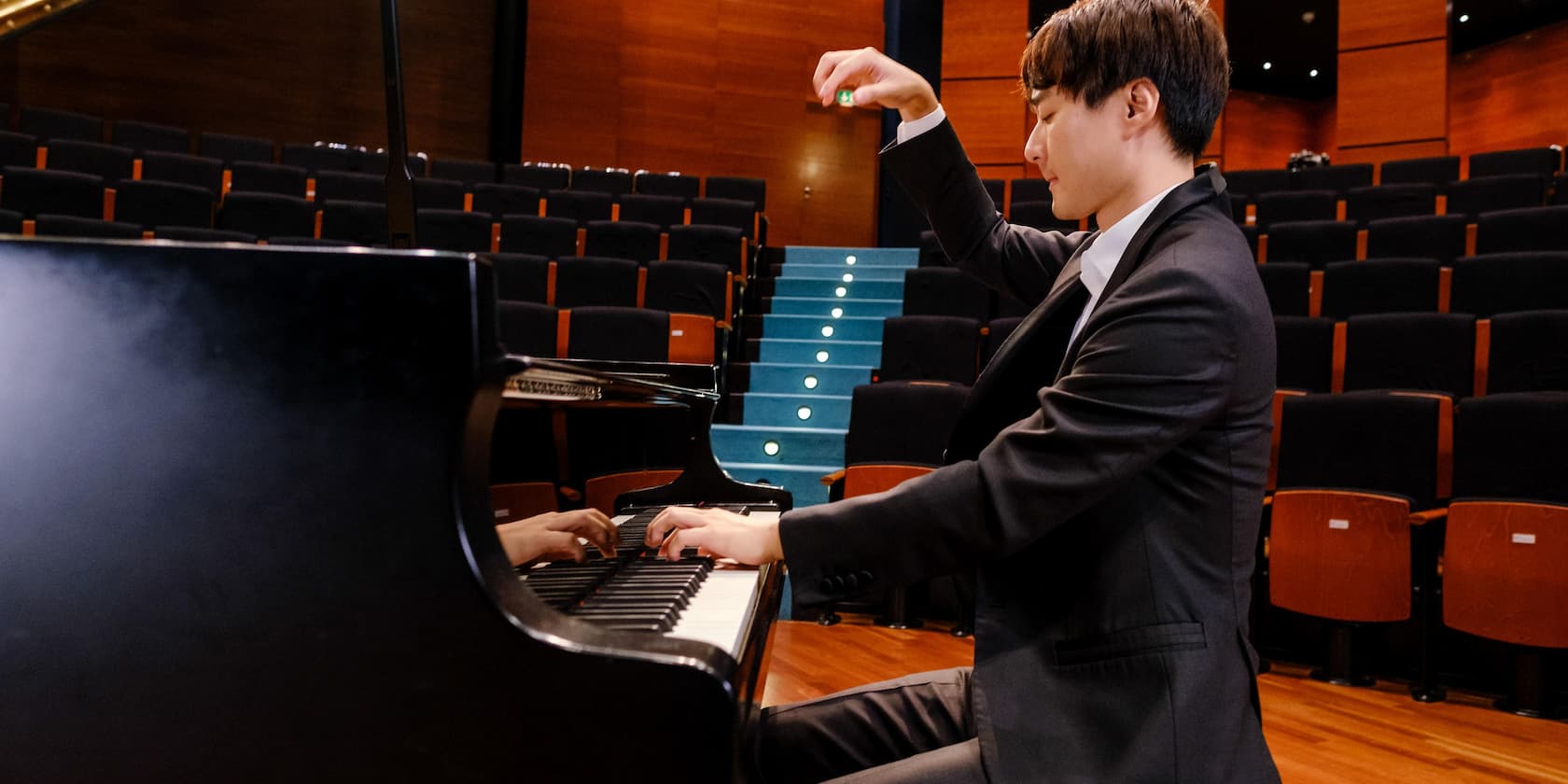 A pianist playing the piano in an empty concert hall.