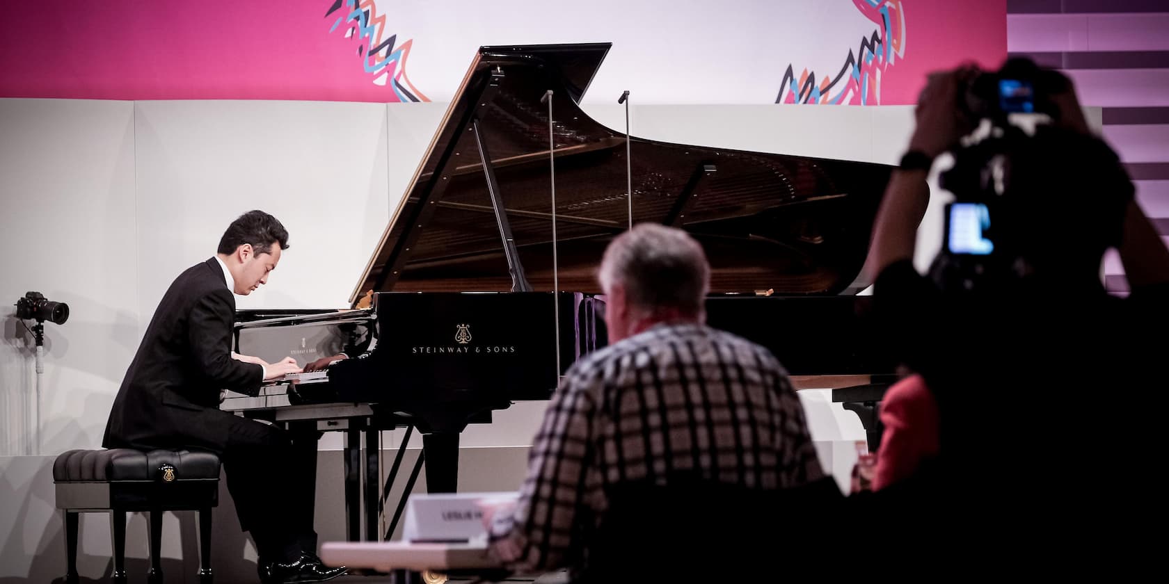 A pianist playing a grand piano in front of an audience.