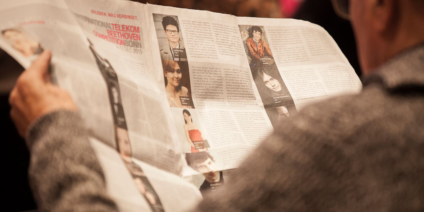 Person reading a newspaper article about the International Telekom Beethoven Competition Bonn.