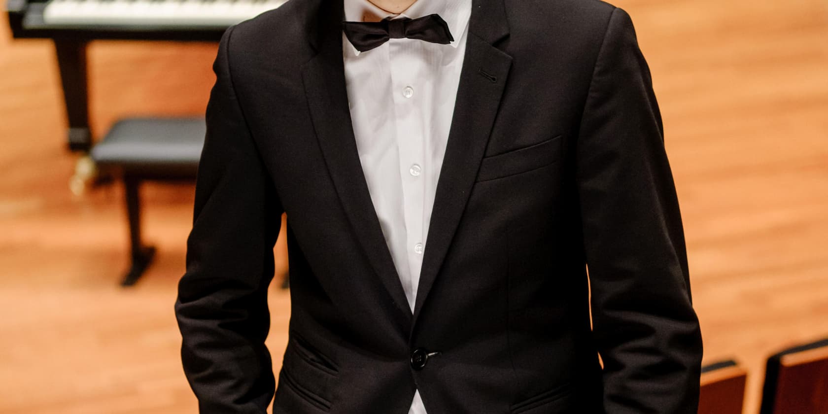 A man in a suit stands in a concert hall.