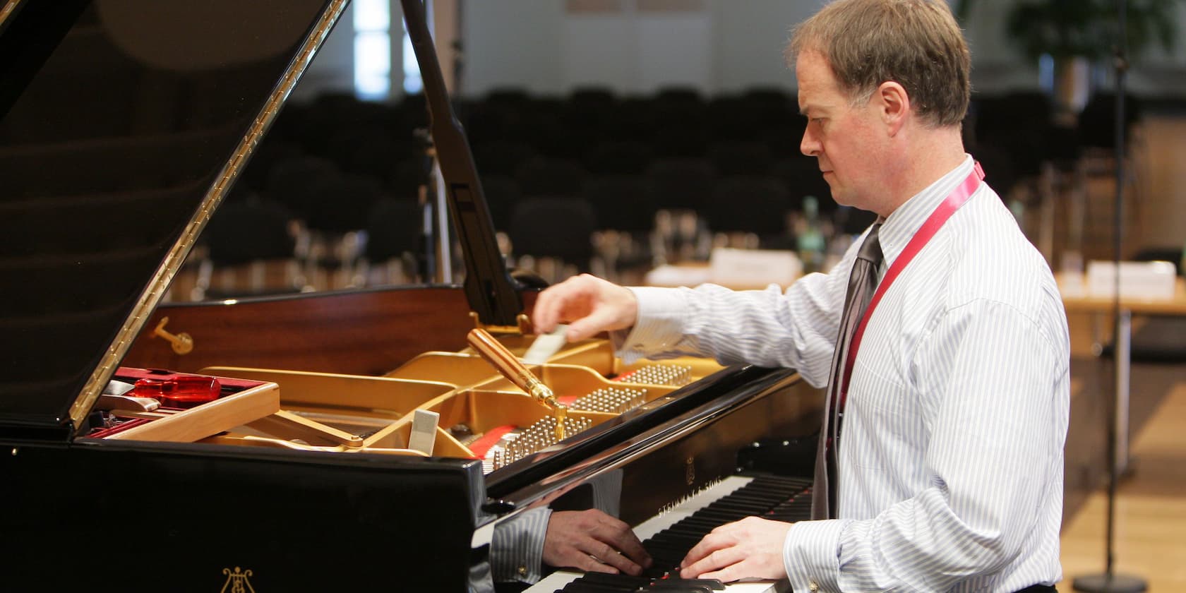 A man tuning a grand piano in a room.