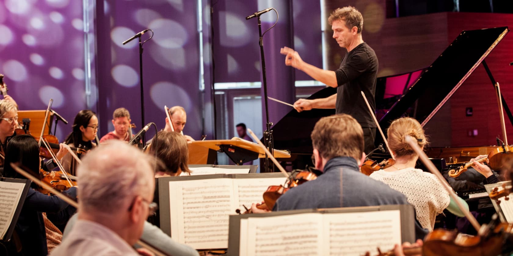 A conductor leads an orchestra during a rehearsal.