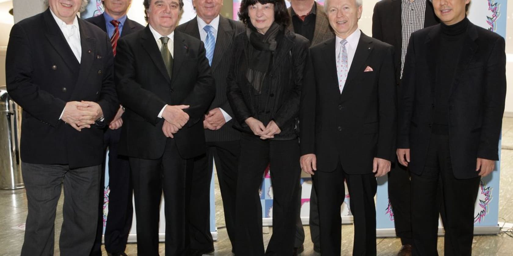 A group of eight people standing next to each other in formal attire.