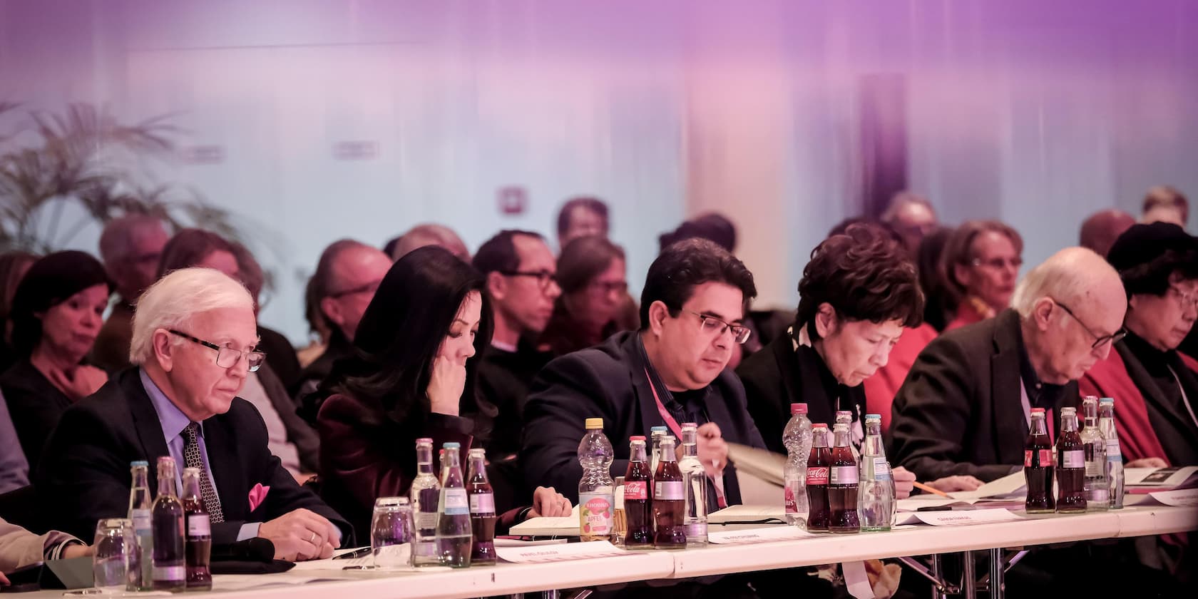 People sitting at a table reading documents during a meeting or conference.